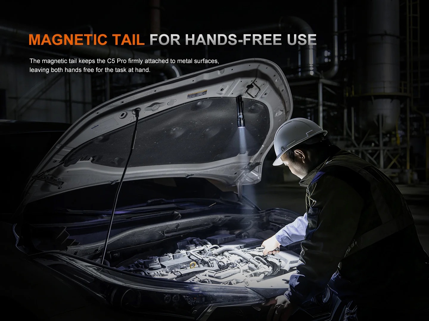 Technician wearing a hard hat inspects a car engine with the hood open in a dark workshop, highlighting a hands-free magnetic tail feature.