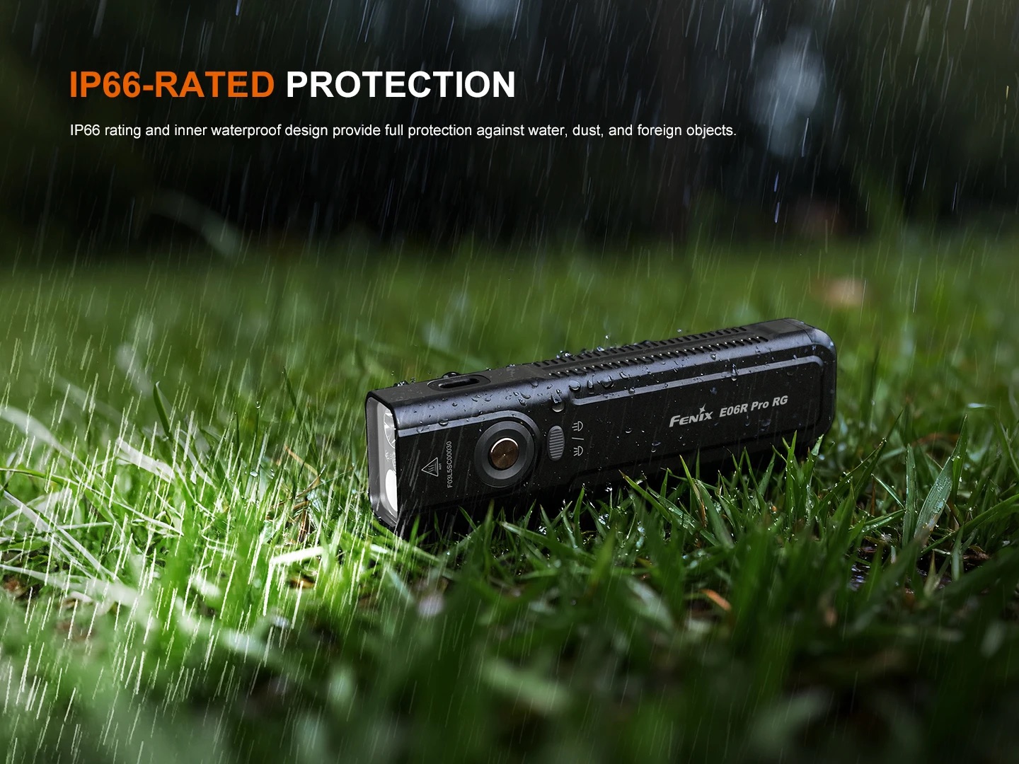 Black Fenix E06R Pro RG flashlight lying in wet grass during rain, illustrating IP66-rated protection in use key idea of rugged waterproof design.