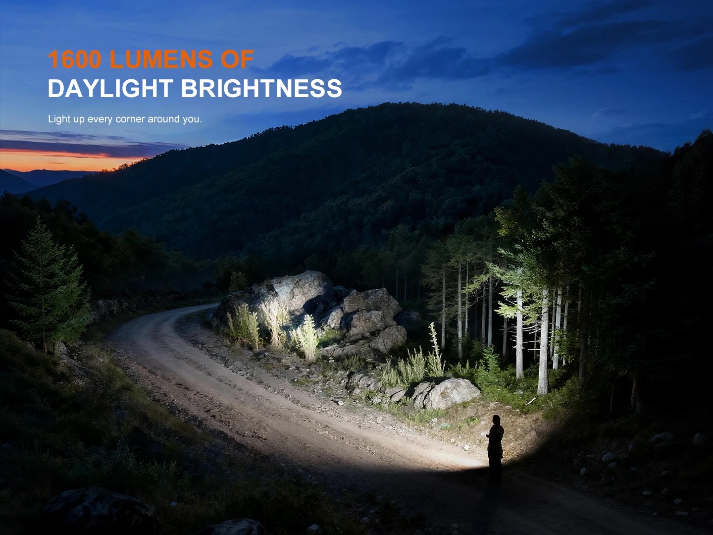 Forest hillside at dusk with a person on a dirt road lit by a bright flashlight beam; headline reads '1600 LUMENS OF DAYLIGHT BRIGHTNESS'