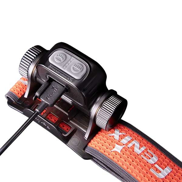 USB-charging battery pack mounted on an orange armband with a cable plugged in