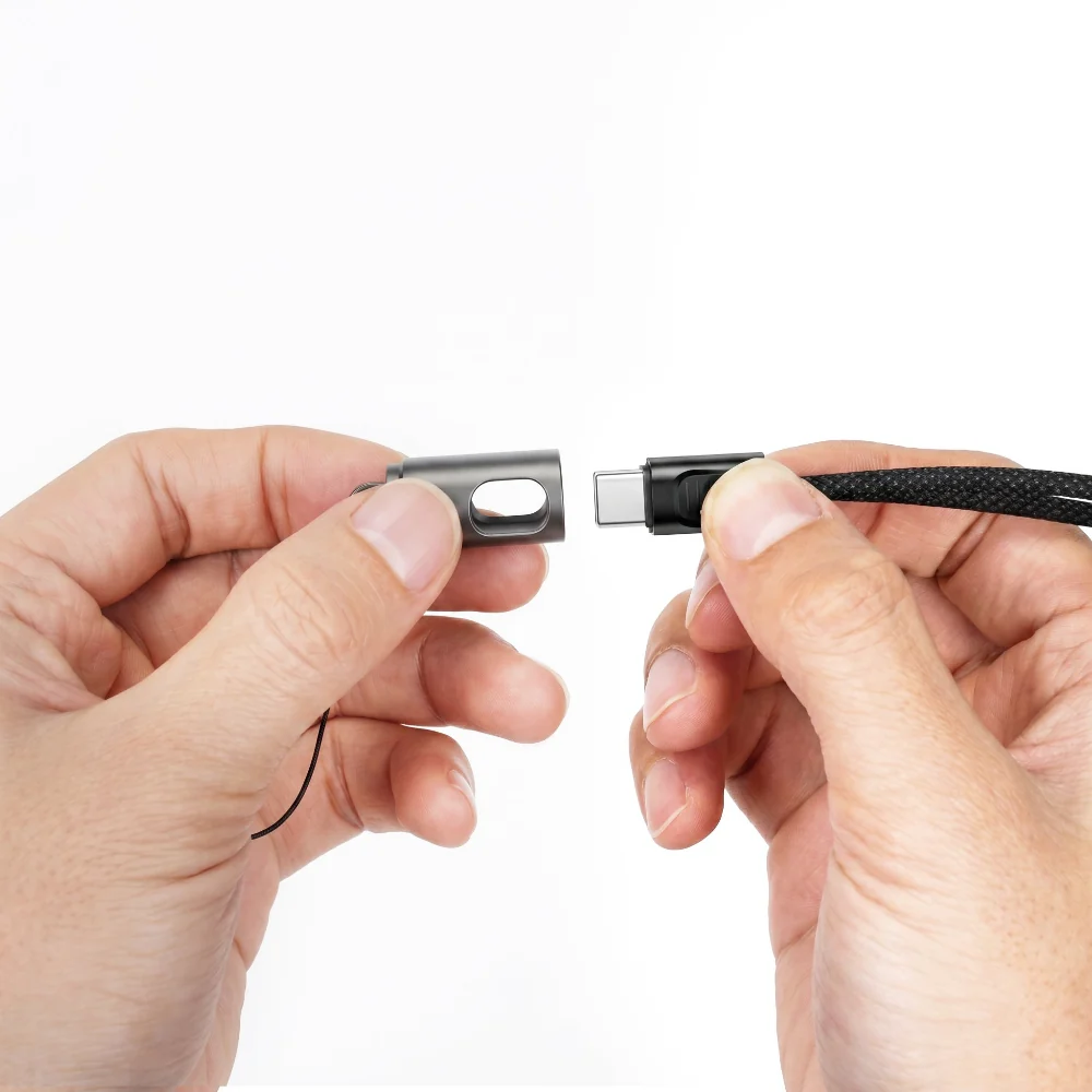 Hands connect a small metal cap to a USB-C charging cable adapter.